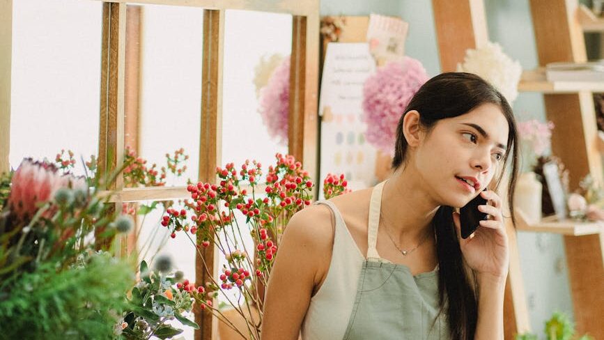 pensive florist talking on mobile phone in shop